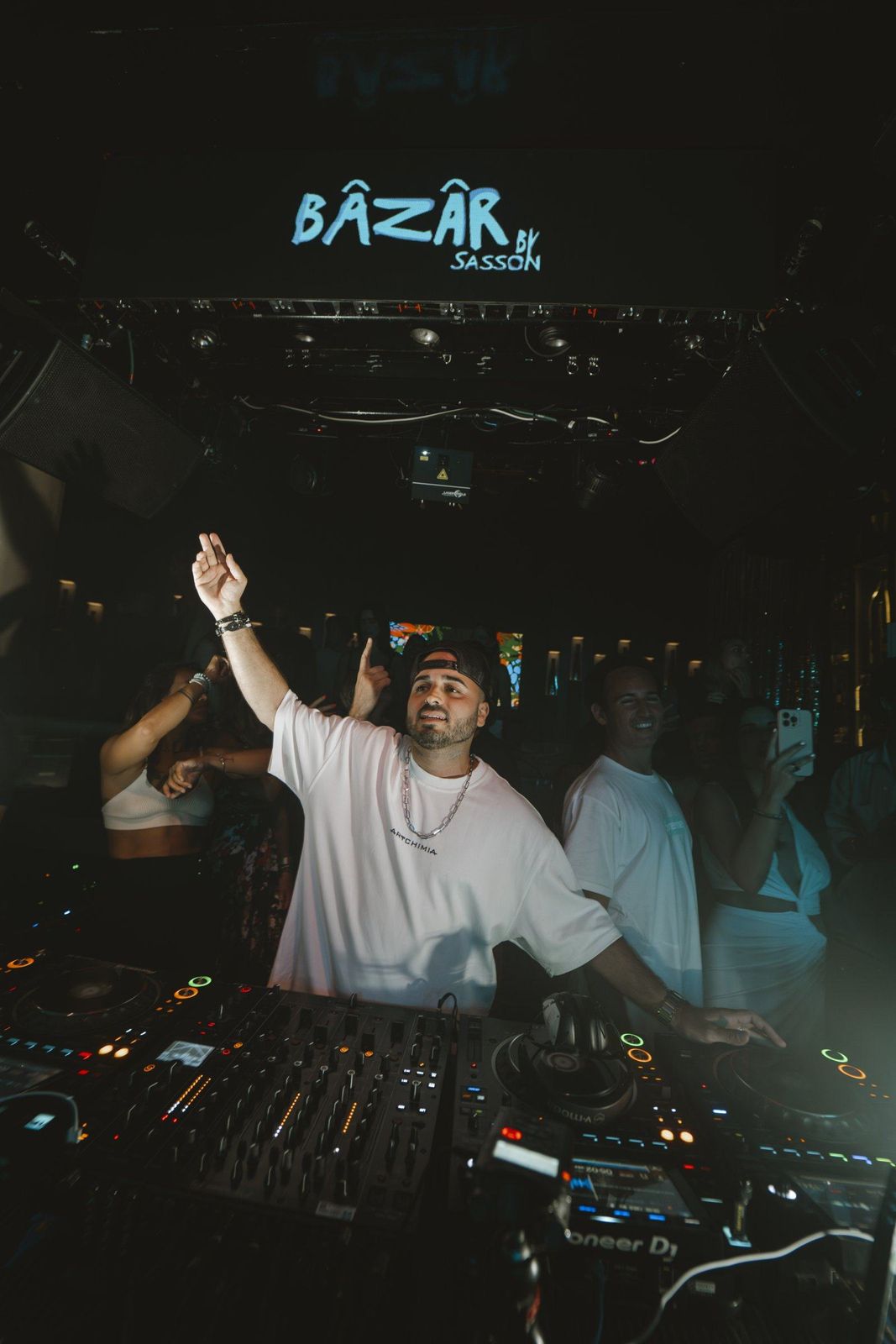 ERAN raising his hand behind the decks in a dark club